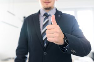 caucasian man in a suit with his thumb up