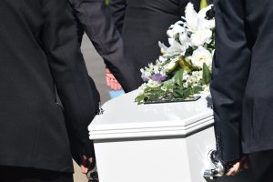 white casket being carried by men in black suits.