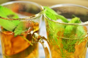 two glasses of tea with peppermint in them.