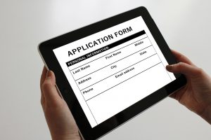 application form on a tablet with hands holding the tablet.