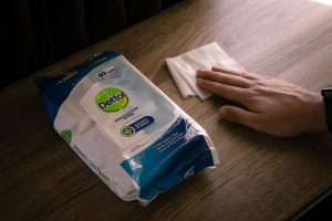 disinfectant wipes on a table with a hand holding a wipe on a table.