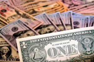 piles of hundred dollar bills with one dollar bill in front of the pile