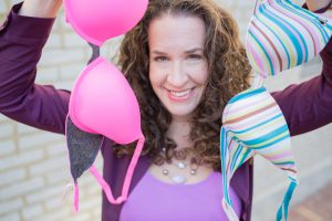 Dana Marlowe holding up two bras, one pink and one multi-colored