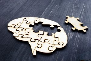 brain in puzzle pieces connected except for one middle part off and placed to the side
