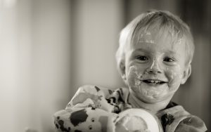 young caucasian kid smiling with yogurt all over his face.