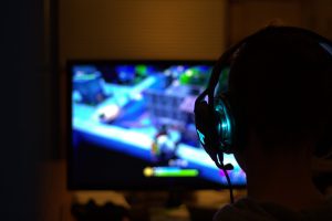 silhouette of a person with a headset on with video games on the screen.