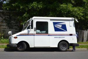 post office car parked on the side of the road.