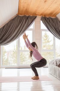 woman standing in a yoga position in her room 