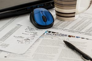 paper with tax incentive in the middle and a computer mouse and pen over the papers.