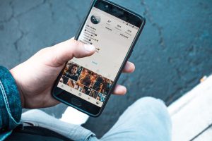 a caucasian hand holding a cell phone with social media on the screen