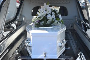 white casket with white flowers on top of it in a car