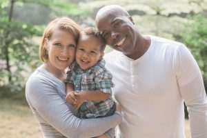 a caucasian woman and afircan american man holding a baby