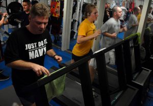 a woman and 2 men running on a treadmill next to each other
