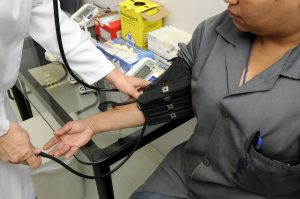 a man sitting down getting his blood pressure checked by a doctor