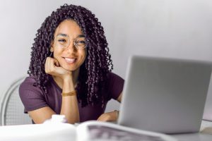 young african american woman smiling with a laptop in front of her.