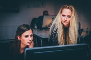 two caucasian women looking at a computer screen.