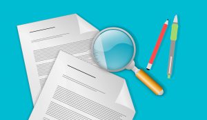 magnifying glass next to papers and pens