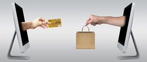 hand with credit card coming out of a laptop to another hand across with a bag coming out of a screen