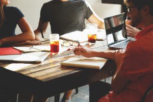 people sitting at a table with books and papers all around 