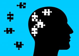 black silhouette of a head with white puzzle pieces in it and the black puzzle pieces next to the silhouette