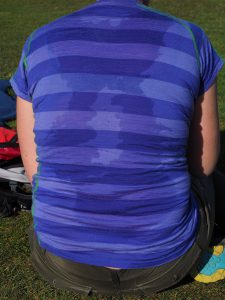 the back of someone sitting down with a blue shirt on soaked in sweat