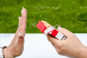woman's hand rejecting a pack of cigarettes in a man's hand.