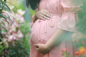 woman in a pink dredd holding her pregnant belly