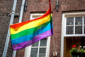 rainbow flag hanging outside of a window of apartment building