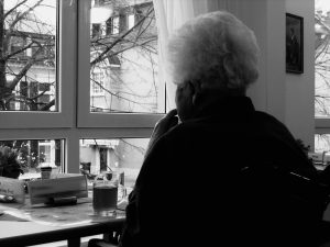 black and white picture of an elderly woman looking out the window