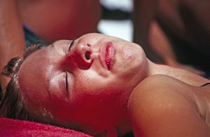 woman sitting outside on the beach tanning