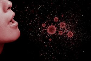person sneezing with red viruses spreading out 