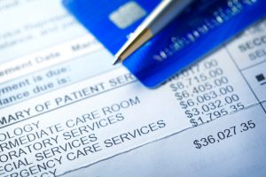large medical bill with a credit card and pen on top of the bill.