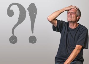 a caucasian man with his hand on his head with a question mark and exclamation mark next to him