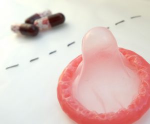 a line split with a pink condom on one side and pills on another side of a line