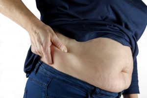 person's belly with their stomach grabbing the fat.