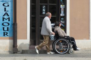 older man pushing an older woman in a wheelchair