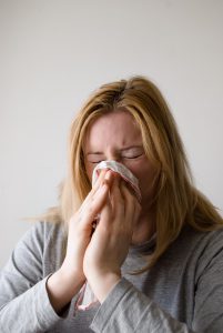 caucasian woman blowing her nose into a tissue