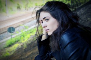 young caucasian woman looking outside with her hand on her head
