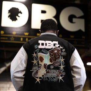 letterman jacket with the letters DBG on it and a picture of a person with scrapes on their face and hands holding a book