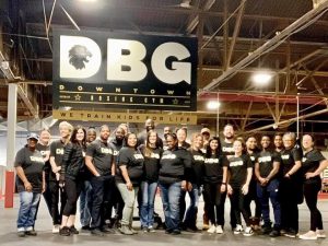a group of people standing next to each other smiling with a DBG banner above them.