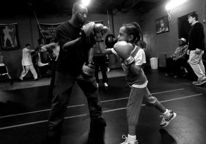black and white photo of Khali and a young girl boxing 