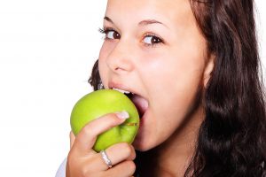caucasian woman biting into a green apple
