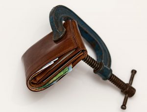 wallet with a black wrench squeezing it