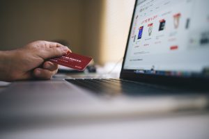 hand with a credit card with a laptop screen open with products on the screen