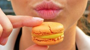 womans lips puckered up with a macaron in front of it
