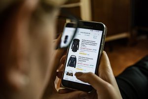 person looking at cellphone with coats and ratings on each 