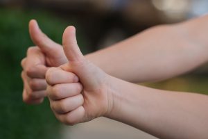 two caucasian hands with their thumbs up