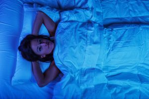 woman laying in bed awake with her hands behind her head
