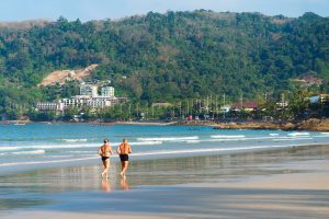 a senior couple running along the beach