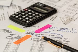 paperwork with a calculator on top and a pen around a circled sentence.
